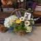 A spring gift basket full of faux flowers with a birch bark Easter bunny gift tag tied to the top.
